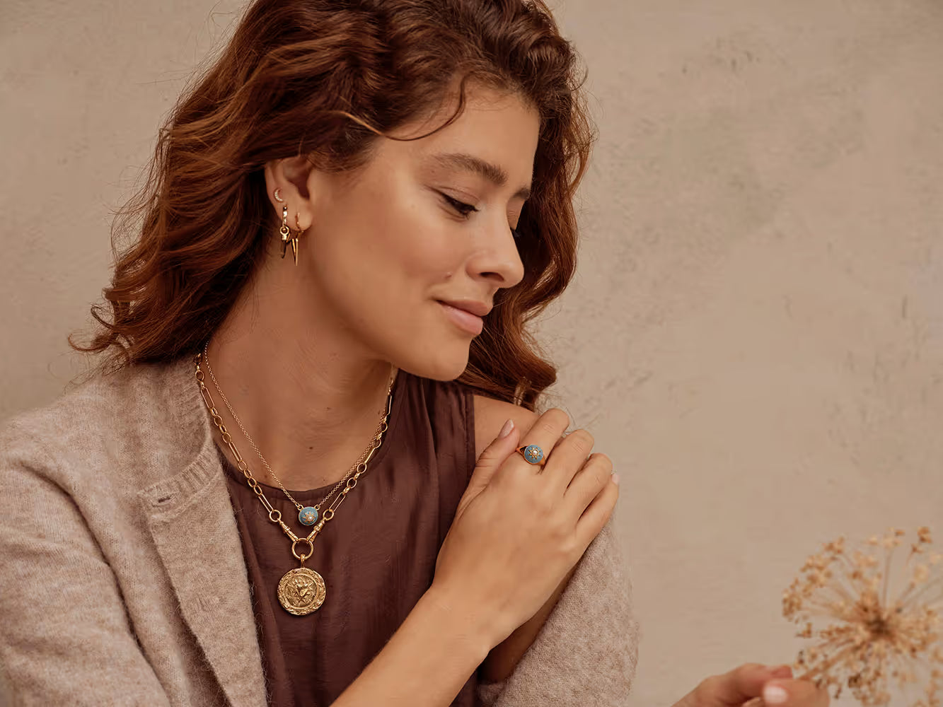 A woman looking into the camera, she's wearing a denim shirt and Harry Rocks jewellery